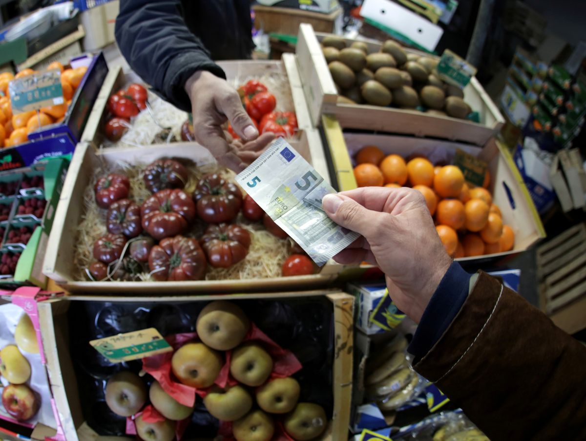 FILE PHOTO: A shopper pays with a euro bank note in a market in Nice